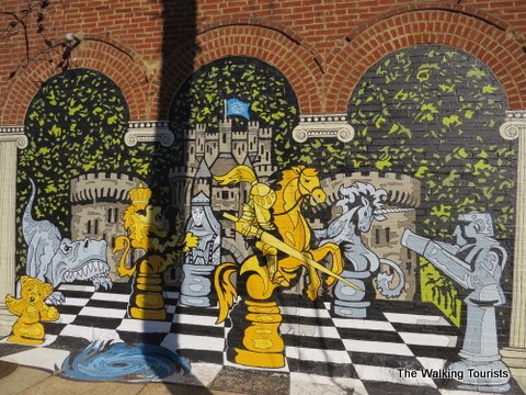 Chess board w/interesting pieces painted on the side of a building 