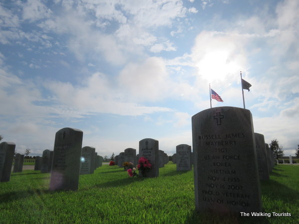 A view of grave markers with US flag behind them at the Kansas Veterans Cemetery