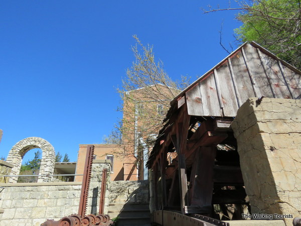 A view of the Old Mill from near the river with a small gray shed in front and limestone dencing