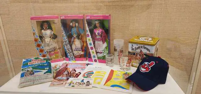Display of racist items, including Barbie dolls as Native Americans, boklets, product container and a baseball team cap.